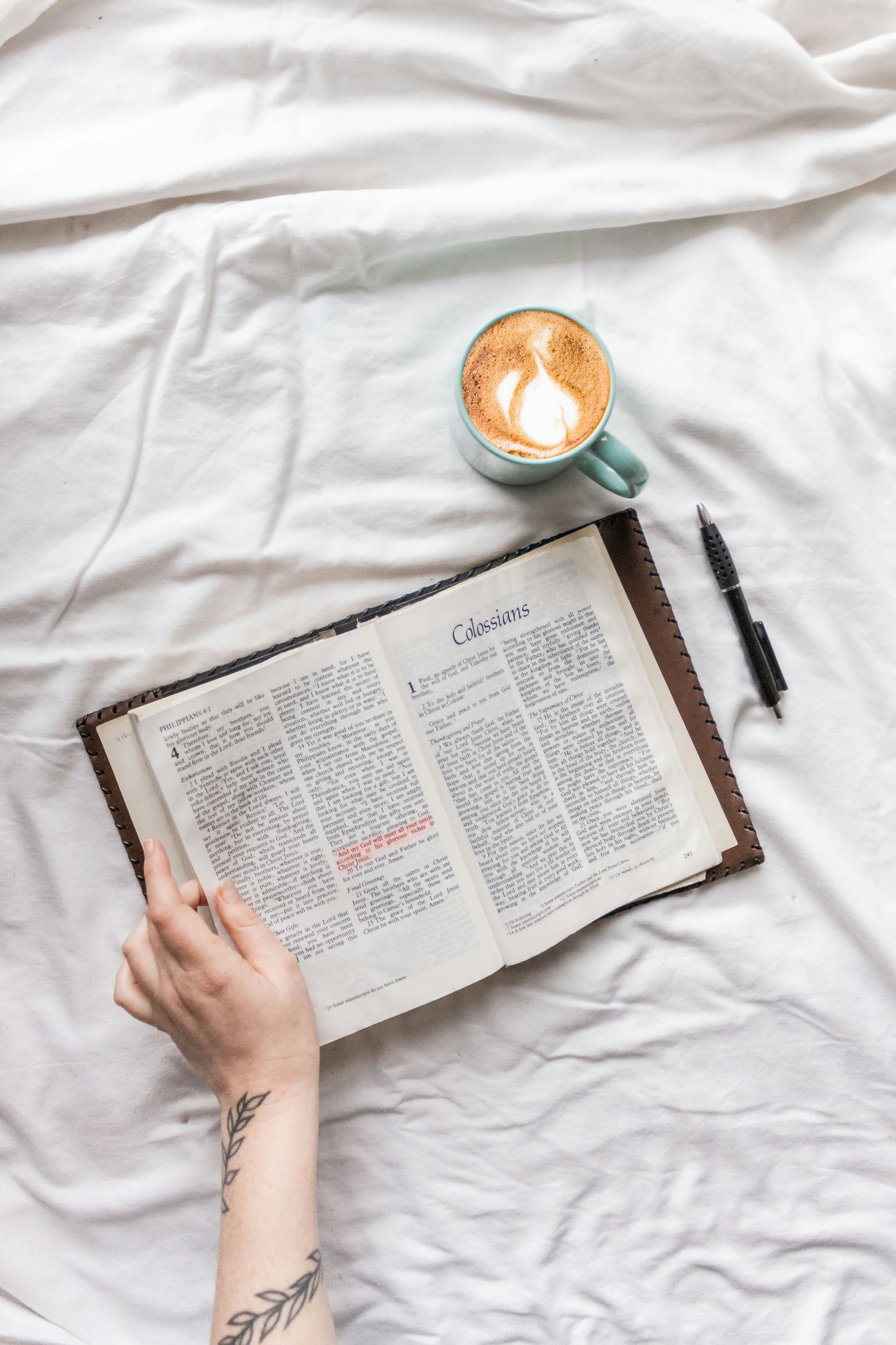 person reading book on white textile